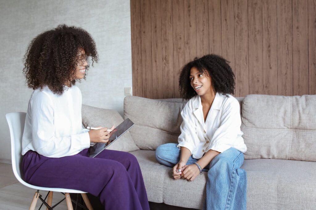pexels-photo-5234582 Two women in a friendly conversation on a sofa, showcasing a relaxed atmosphere.